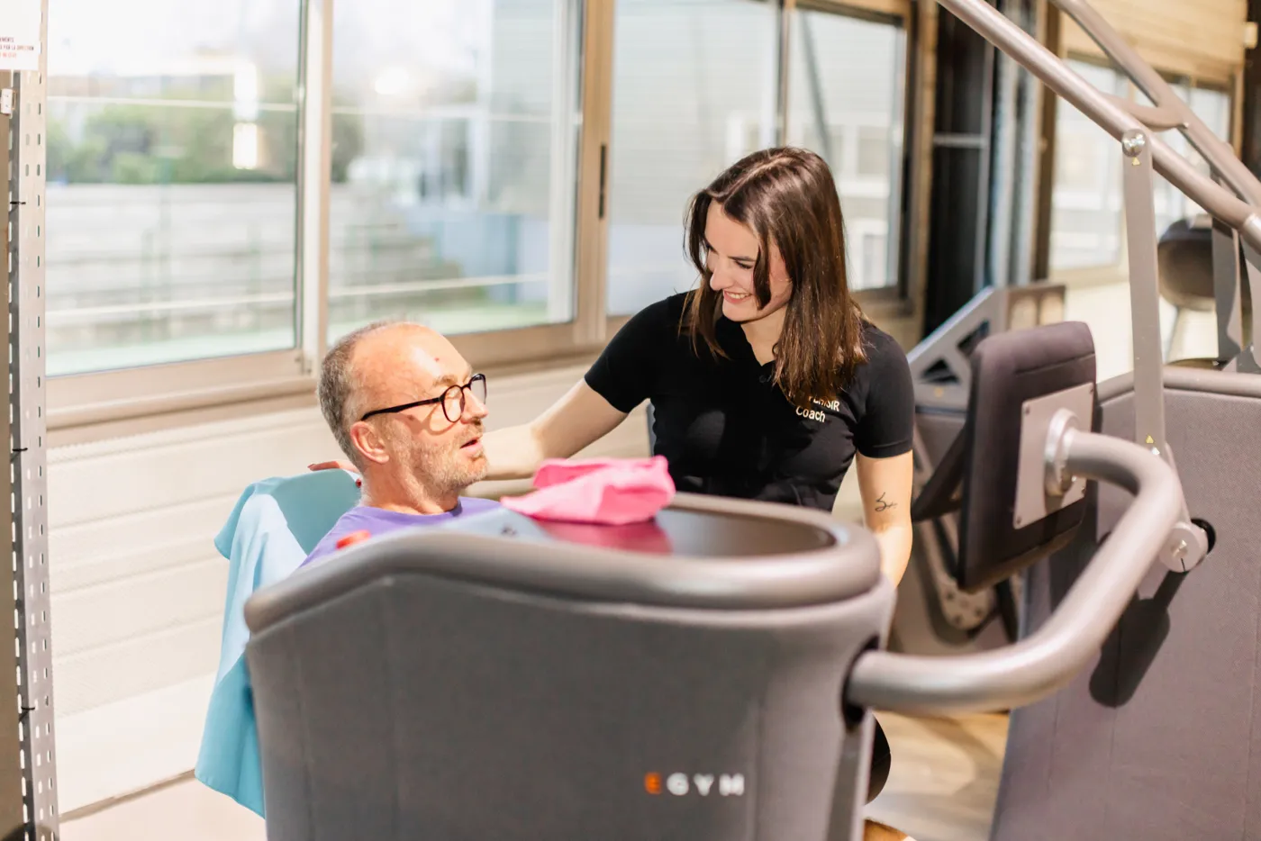 Coach accompagnant un adhérent sur une machine EGYM