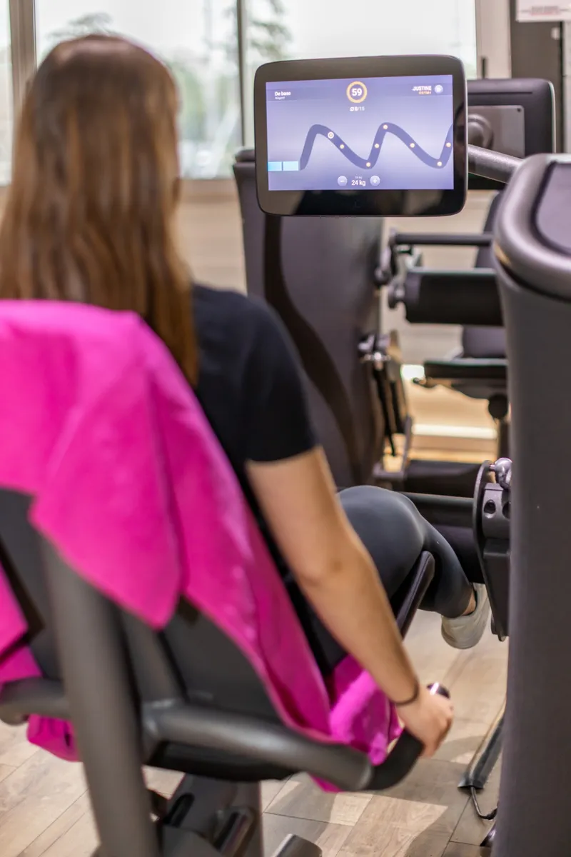 Adhérente sur un appareil EGYM, avec son programme affiché à l'écran