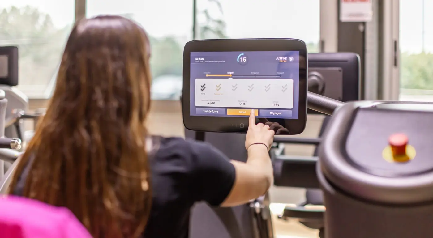 Adhérente réglant une machine connectée EGYM